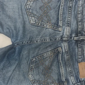 Bootcut jeans från Perfect Jeans, blå - Snygga blå bootcut jeans från Perfect Jeans med coola broderade bakfickor. Klassisk femficksmodell i jeansmaterial, perfekt för dig som gillar en lite utsvängd look. Färgen är mellanblå denim och passformen är normal.