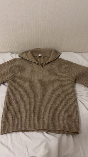 Beige stickad half zip-tröja Zara - Säljer en beige stickad tröja från Zara med ribbad struktur och half zip-dragkedja vid kragen. Tröjan har långärmade ärmar och en loose passform som ger en chill vibe. Perfekt för höst och vinter när man vill vara både varm och snygg.