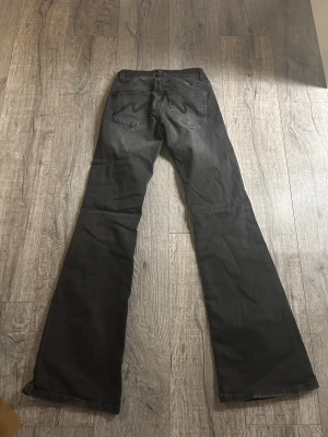 Svarta bootcut jeans med slitningar - Svarta jeans från Nelly med bootcut passform och slitna detaljer vid knäna. Jeansen har klassisk femficksdesign och snygg broderad bakficka. Materialet är jeans med lätt tvättad look och knäppning fram.