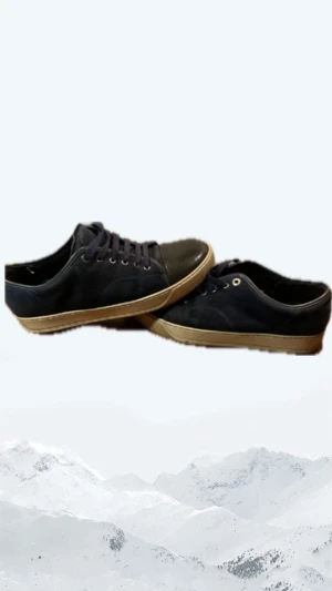 Mörkblå sneakers från Lanvin - Snygga mörkblå sneakers från Lanvin med ovandel i mocka och tåparti i svart skinn. Skorna har rund tå, platt vit sula och klassisk snörning. Perfekt för dig som gillar stilrena och exklusiva sneakers med en lyxig känsla.