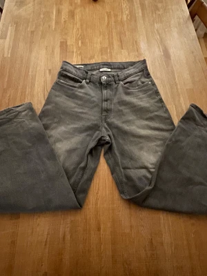 Grå baggy jeans från Vailent - Säljer ett par grå baggy jeans från Vailent med klassisk femficksdesign och raka ben. Jeansen har en cool tvättad look och är tillverkade i slitstarkt denim. Passar dig som gillar avslappnad stil och bredare siluett.