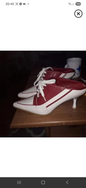 Rödvita klackskor med snörning - Unika klackskor i rött och vitt med spetsig tå och snörning framtill. Skorna har låg klack och cool retrovibe, perfekta för dig som vill sticka ut. Tillverkade i syntetmaterial med kontrasterande färgblock och vita skosnören.