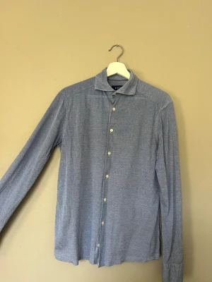 Blå skjorta från Eton slim fit - Snygg blå skjorta från Eton i slim fit med klassisk krage och vita knappar. 