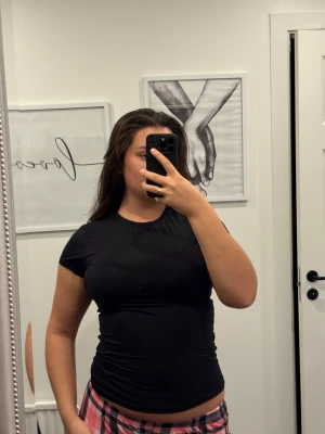 Svart tight t-shirt i stretch - En svart, tight och figurnära t-shirt med korta ärmar. T-shirten har rund halsringning och är gjord i ett stretchigt material som sitter snyggt mot kroppen. Perfekt för dig som gillar en enkel och clean look. L/XL passar M med.