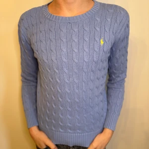 Ljusblå Ralph Lauren kabelstickad tröja  - En tvärfet ljusblå Ralph Lauren kabelstickad tröja | storlek 14-16/L i barnstorlek, motsvarar ca xxs-xs i vuxenstorlek | ungefärliga mått:  37cm axelbredd, 54cm full längd, 50cm ärmlängd, alla mått är tagna med plagget platt på marken | sparsamt använd, skick 9/10, inga defekter | obs bilder från han som jag köpte den av. Vid fler bilder så hör av er///Anton