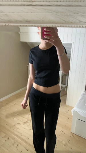 Svart croppad t-shirt topp - En svart croppad t-shirt topp med korta ärmar och rund halsringning. Tillverkad i mjuk bomull, perfekt för en avslappnad och stilren look. Enkel design som är lätt att matcha med olika outfits.