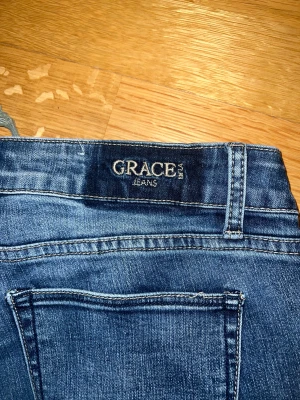 Mörk blåa jeans med snörning - Grace jeans, aldrig använda. Förstora för mig därför säljer jag dem. Dem har en vit fläck vid knät men den drar inte till sig uppmärksamhet, fanns där när jag köpte dem.