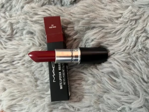 MAC Ruby Woo matt läppstift - MAC Matte Lipstick i färgen Ruby Woo 707. Ett ikoniskt rött läppstift med matt finish, klassisk hylsa i svart och silver. Kommer i originalförpackning. Perfekt för dig som vill ha en djärv och snygg röd färg på läpparna.