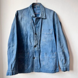 Blå overshirt i denimstil - Klassisk blå overshirt med tre stora utanpåfickor och knäppning framtill. Jackan har en rak passform, enkel krage och är tillverkad i ett robust bomullstyg som påminner om denim. Perfekt för lager-på-lager och en avslappnad look.