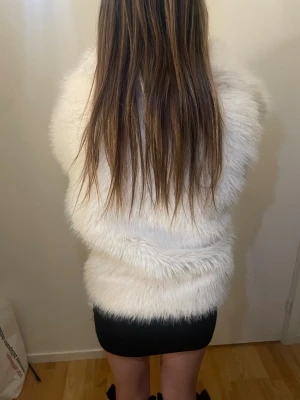 Vit fluffig pälsjacka - Säljer en supermjuk och fluffig vit pälsjacka med lång ärm. Jackan har en oversized passform och är perfekt för dig som vill sticka ut med en trendig look. Den är gjord i fuskpäls och känns riktigt lyxig och varm.