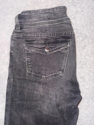 Grå jeansbyxor från Gina Tricot - Snygga lowwaist grå jeansbyxor från Gina Tricot med dubbla knappar i midjan. Jeansen har raka/flare ben och är tillverkade i mjukt denimtyg med lätt tvättad look.