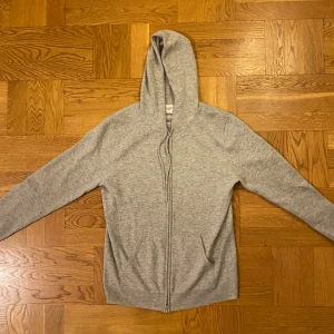 Grå zip hoodie i kashmir från John Henric - Mjuk och lyxig grå hoodie från John Henric i kashmir. Tröjan har huva med snörning, dragkedja framtill och två fickor. Perfekt för dig som gillar stilren och bekväm design. Passformen är normal för en strlk M👍
