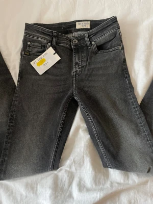 Svarta skinny jeans från Tiger of Sweden - Snygga svarta jeans från Tiger of Sweden med skinny passform och klassisk femficksdesign. Jeansen har en mörk tvätt med subtila slitningar och silverfärgad knapp framtill. Perfekt för dig som gillar stilrena och moderna jeans.