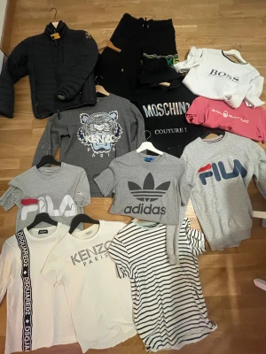 Grå sweatshirt med tiger från Kenzo -  Färg= svart Storlek= XS her sitter större i storleken  Nypris 4800kr Kom med bud Skick 9/10 Kenzo sweatshirt  Färg= Grå  Storlek= XS (Herr)  Nypris= 2900kr  Mitt pris= 700kr skick 9/10  Hugo boss sweatshirt  Färg=vit Storlek= Nypris=ca 800kr Mitt pris 250kr Ralph Lauren sweatshirt  Färg= Svart med guld emblem  Storlek= 152cm (stor i storleken)  Skick= 9/10  Nypris 600kr  Mitt pris= 250kr (kids) Kenzo T-shirt  Färg= Vit  Storlek= 140cm (kids) Nypris= 700kr Mitt pris= 200kr  Skick 7/10   Kenz