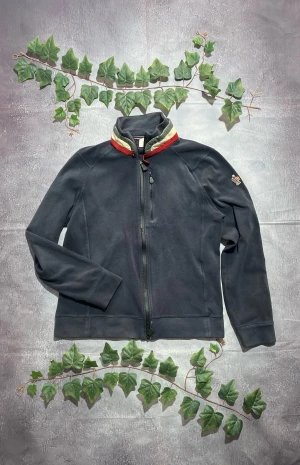 Moncler Cardigan i Navy Storlek XL [ÄKTA] - 🎨 Färg: Mörkblå / Navy med Röd och Vita detaljer 📏 Storlek: XL men passar L♻️ Skick: 7/10 – lättare bruksspår men inga skador eller fläckar 🧵 Material: Mjuk, fleeceliknande tygkonstruktion ✨ Detaljer: • Hög krage med röd/vit dekorlist • Helsydd mjuk design utan quiltning • Bröstficka med dragkedja • Dragkedja framtill • Moncler-patch på vänster ärm • Bekväm och följsam modell – perfekt som lätt jacka eller mellanlager ‼️ Skickas dagen efter köpet genomförs! ‼️