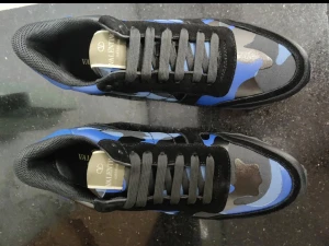 Valentino Garavani blå sneakers - Snygga sneakers från Valentino Garavani med blått och svart camouflage-mönster. Skorna har rund tå, platt sula och snörning. Ovandelen är i textil och mocka med svarta detaljer och logotyp på plösen. Perfekt för dig som gillar streetstyle och exklusiva märken.