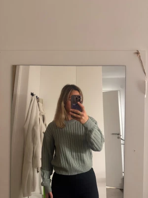 Ljusgrön ribbstickad tröja - Säljer en ljusgrön ribbstickad tröja med rund hals och långa ärmar. Tröjan har en relaxed fit och är perfekt för lager-på-lager. Enkel och stilren design som passar till det mesta.