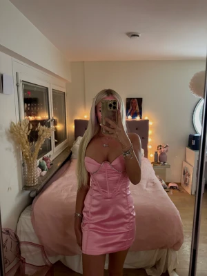 Rosa festklänning - Superfin rosa festklänning från Dressmezee med bygelkupor och glittriga rhinestone-band. Ger en riktig Barbie-vibe och sitter otroligt smickrande på kroppen 💓✨ Det är ett litet hål under bröstet, väldigt diskret och syns knappt. (se bild) Rhinestones hänger lite löst på högra axelbandet, inget som syns heller när man har den på sig! (se bild) I övrigt i fint skick. - Passar XS Skriv privat för fler bilder eller frågor 🫶🏽