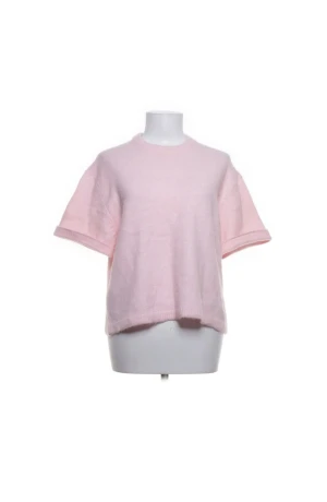 Ljusrosa stickad kortärmad tröja - Superfin ljusrosa stickad tröja med korta ärmar och avslappnad passform. Tröjan har rund halsringning och ribbade kanter vid ärmslut och nederkant. Perfekt för lager-på-lager och en söt touch till din outfit.