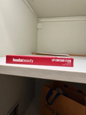 Huda Beauty Lip Contour Stain Cherry Red - Lip Contour Stain från Huda Beauty i färgen Cherry Red. En lätt lip tint med lång hållbarhet, infuserad med arganolja för extra vård. Kommer i en slim röd förpackning, perfekt för att skapa definierade och färgstarka läppar. HELT NY