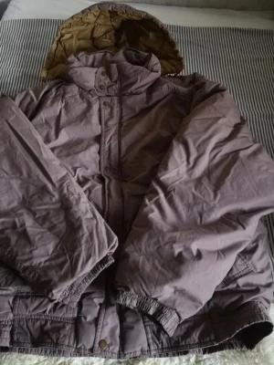 Dunjacka /Vinterjacka I Stl XL  - Stl XL Mått: längd 75 cm ( utan huvan ) armhåla till armhåla 73 cm Från krage till muddar 85 cm Kedjan är trasig men jackan stängs med knappar utan problem. Det finns två fickor framtill och en innerficka. Djur och rökfritt hem.