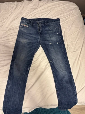 Diesel Industry blå jeans -  Säljer ett par klassiska blå all-over slitna jeans från Diesel Industry. De har fem fickor, normal passform och midwaist. Jeansen är i ett robust denimtyg och har snygga slitningar för en avslappnad look.