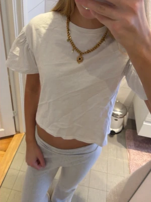 Vit croppad t-shirt med puffärm - Säljer en vit croppad t-shirt med puffiga korta ärmar. Toppen har rund halsringning och är gjord i mjuk bomull. Perfekt att styla med jeans eller mjukisbyxor för en chill look.(den är barn storlek och är för liten för mig så därför är den kortare än vad den skulle varit på ett barn)