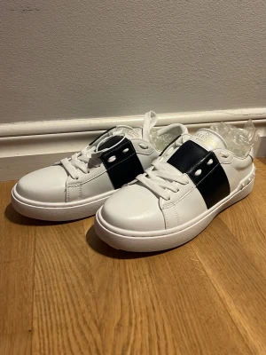 Valentino Garavani vita sneakers med svart detalj - Snygga vita Valentino Garavani sneakers, väldigt lika originalet och sitter otroligt bekvämt. 