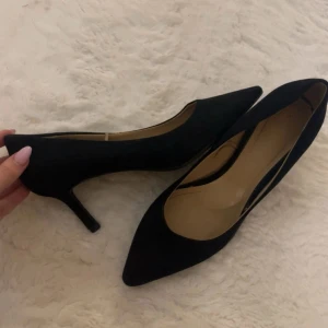Svarta pumps med spetsig tå - Säljer ett par klassiska svarta pumps med spetsig tå och låg klack. Skorna har en elegant och tidlös design som passar perfekt till många olika outfits. Materialet känns mjukt och de har en smal siluett🥰