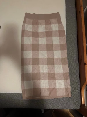 Beige och vit rutig kjol Gina Tricot - Supersnygg rutig kjol från Gina Tricot i beige och vitt. Kjolen är stickad och har en rak, kroppsnära passform med bred resår i midjan. 