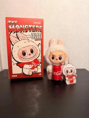 Popmart The Monsters Labubu x Coca-Cola – Happy Factor  - Säljer Labubu “Happy Factor” från Pop Mart’s Coca-Cola The Monsters-serie. En charmig figur där Labubu sitter med en klassisk Coca-Cola-burk, klädd i seriens karakteristiska fluffiga dräkt.  Detaljer: 	•	Original Pop Mart 	•	Coca-Cola samarbete 	•	Vinylfigur med mjuk, fluffig dräkt 	•	Med nyckelring/strap 	•	I fint skick  En populär modell bland Labubu-samlare och ett fint tillskott till både samling och vardagsaccessoarer. Skickas välpackad eller kan hämtas enligt överenskommelse.