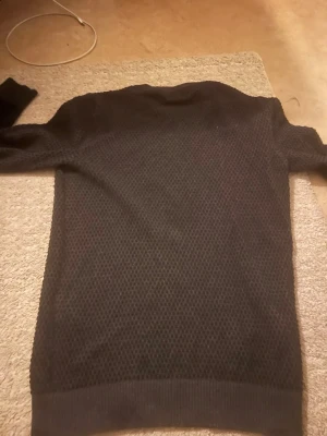 Mörkgrå tröja från Jack & Jones storlek S  - Säljer en mörkgrå stickad tröja från Jack & Jones i storlek S. Tröjan har ett diskret mönster, rund halsringning och ribbade muddar vid ärmslut och nederkant. Perfekt för kyligare dagar och enkel att matcha med jeans eller chinos.