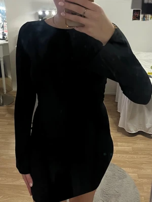 Svart kort klänning - Säljer en svart kort tajt klänning med lite utsvängda armar och öppen rygg. Aldrig använd men har ingen prislapp på.