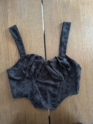 Svart broderad korsett med dragkedja - Svart korsett med breda axelband och broderade blommor. Storlek S, knappt använd. Köpt utomlands.