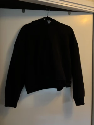 Svart hoodie - Svart hoodie, något mer åt de kortare hållet så passar även S
