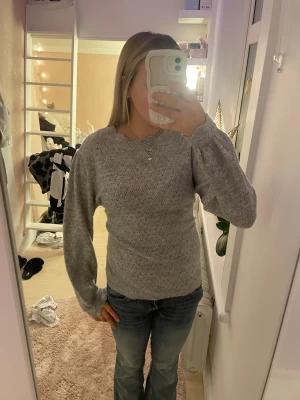 Grå stickad tröja från Stories S - Mysig grå stickad tröja från Stories i storlek S. Tröjan har ett diskret hålmönster, rund hals och långa ärmar med lite puff vid axlarna.❤️