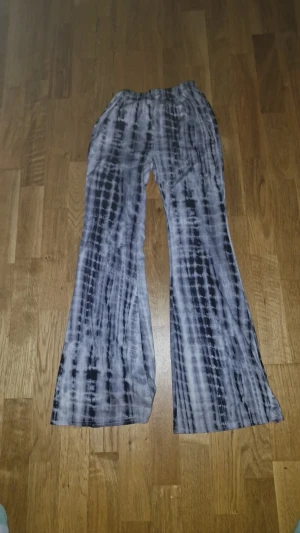 Svarta och vita bootcut byxor, 11-12 år från shein - Säljer ett par coola bootcut byxor med svart och vit batikmönster. Byxorna har elastisk midja och är tillverkade i ett mjukt och stretchigt material som känns skönt mot huden. Perfekt för dig som gillar unik stil och bekväma plagg.säljer den för att det är för litet för mig