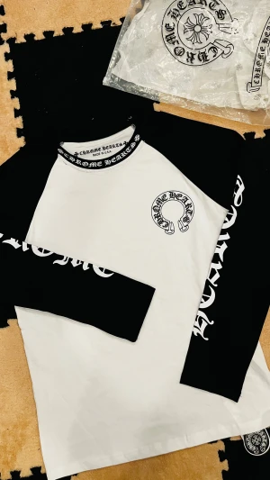 Chrome Hearts svartvit långärmad tröja - Snygg långärmad tröja från Chrome Hearts med svartvita kontraster och tryck på både ärmar och bröst. Rund hals med logotypdetaljer och coolt grafiskt tryck. Perfekt för dig som gillar streetwear och vill sticka ut med en unik design.