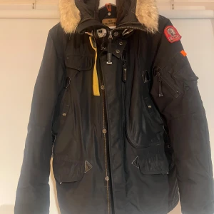 Parajumpers parka - Parajumpers parka med päls och flera fickor samt snygga detaljer som den gula remmen och märket på ärmen. Jackan har löstagbart foder som gör den lätt att tvätta. Använd men i bra skick. Mycket varm och go vinterjacka. Storlek Small. Skicka gärna PM för fler bilder. 