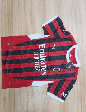 AC Milan fotbollströja Puma röd/svart - Säljer en officiell AC Milan matchtröja från Puma med klassiska röda och svarta ränder, vit krage och detaljer. Tröjan har korta ärmar, klubbmärke på bröstet och Emirates Fly Better som sponsortryck. Perfekt för dig som älskar Serie A och Milan.