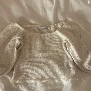 Vit croppad blus från NLY - Säljer en söt vit croppad blus från NLY med puffiga, broderade ärmar och smockad kropp. Blusen har en feminin offshoulder-design och vågig kant nedtill. Perfekt för vår och sommar, superfin till jeans eller kjol!