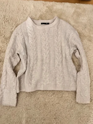 Beige stickad tröja med flätmönster - Säljer en mysig beige stickad tröja från lager 157 i storlek M. Tröjan har ett klassiskt flätmönster och ribbade muddar vid ärmslut och nederkant. Perfekt för kyliga dagar och passar dig som gillar en enkel men snygg stil.