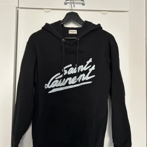 Saint Laurent Hoodie - Säljer nu min Saint Laurent hoodie. Köpt här på plick och kan inte garantera att den är äkta etftersom den saknar vissa tags. Därav är priset lägre. Tröjan är fortfarande i väldigt bra skick och går lätt att bära. Storlek S och sitter som en S/Xs