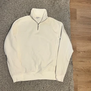 Vit half zip tröja från Zara - Vit långärmad tröja från Zara med hög krage och half zip-dragkedja framtill. Tröjan har aldrig använts utomhus då den är lite för stor för mig. Tröjan är tillverkad i mjuk bomull. Perfekt för dig som gillar minimalistisk stil och vill ha något som funkar året runt.