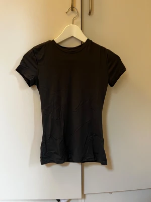 Mörkgrå t-shirt från H&M, storlek S - En stilren mörkgrå  t-shirt från H&M i storlek S. Modellen är klassisk med rund hals och korta ärmar. Materialet är mjukt och stretchigt, perfekt för en enkel och clean look. Passformen är normal och t-shirten är helt enfärgad utan detaljer.