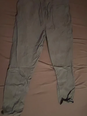 Grå linnebyxor Jack & Jones S - Snygga grå linnebyxor från Jack & Jones i storlek S. Byxorna har avslappnad passform, elastisk midja med snörning och är tillverkade i mjukt linnematerial. Perfekta för chill dagar och har en enkel, stilren look.