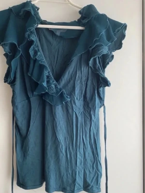 Blus med volang/ spets  - Bedårande blus i storlek 10 (ca S/36). Bra skick! Grön/blå nyans (teal).