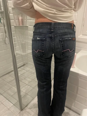 Mörkblå bootcut jeans Replay - Säljer ett par mörkblå bootcut jeans från Replay med låg midja. Jeansen har klassiska fem fickor och snygga detaljer med ljusrosa sömmar på bakfickorna. Materialet är jeans i bomull och de har en sååå snygg passform 💙💙modellen är 164 cm lång 