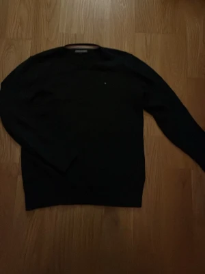 Tommy Hilfiger tröja - Klassisk svart tröja från Tommy Hilfiger. Enkel design med diskret logga på bröstet och rund halsringning. Perfekt till jeans för en clean och stilren look. Passar som xs. Inga fläckar eller hål
