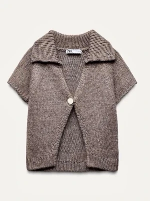 Beige stickad kofta från Zara - Kortärmad stickad kofta från Zara i beige ton. Koftan har en stor krage, ribbade detaljer och stängs med en knapp framtill. Perfekt för lager på lager och ger en chill men ändå stilsäker vibe.